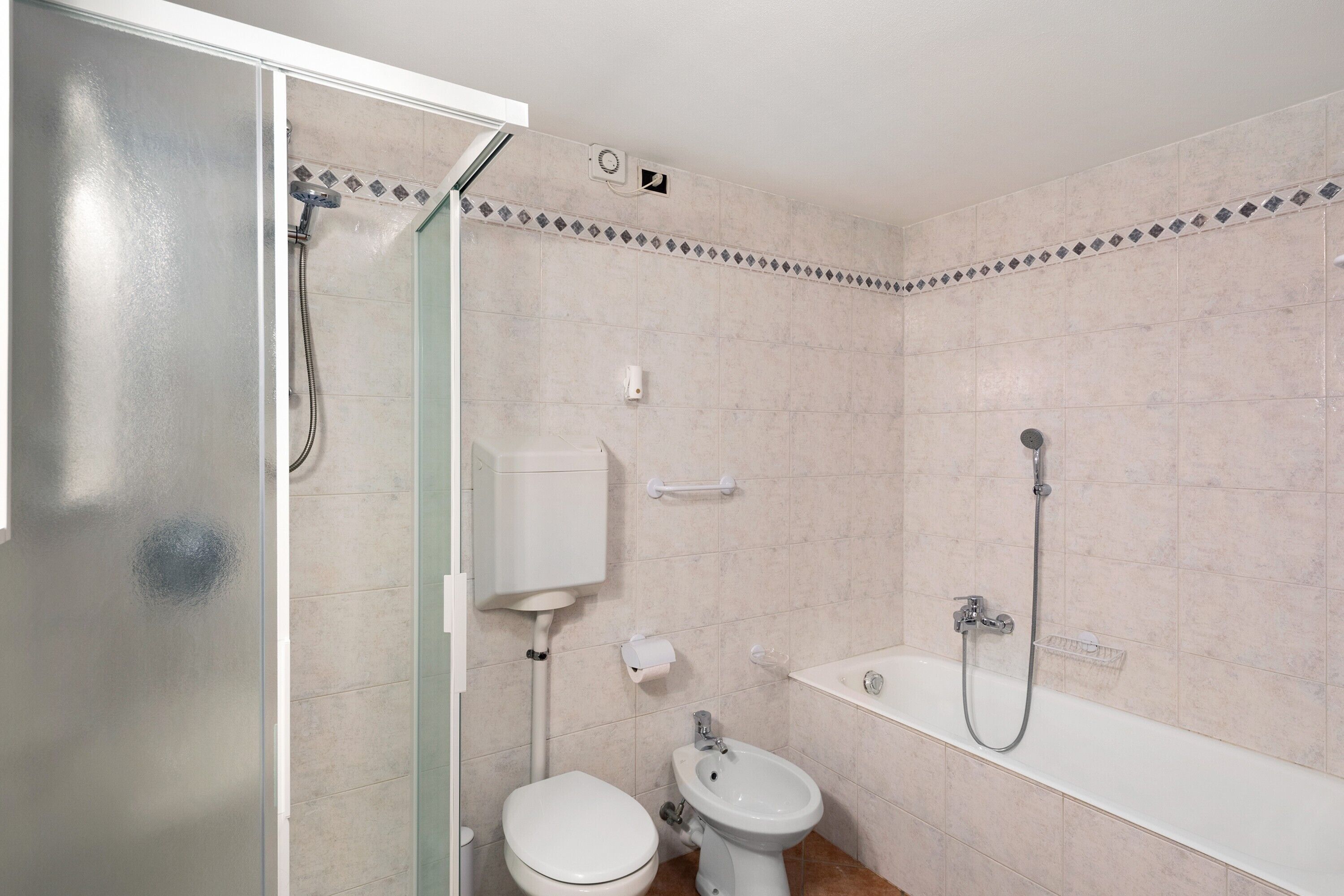 Een badkamer met toilet, bidet en douche.