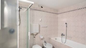 Een badkamer met toilet, bidet en douche.
