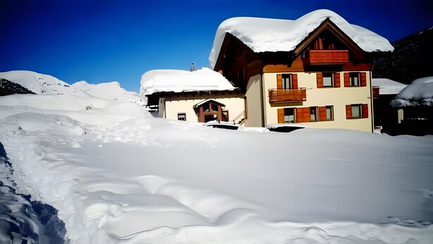 Eine mit Schnee bedeckte Lodge mit Holzbauweise, einem Balkon und einem Blick auf die Berge.