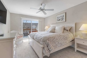 A bedroom with a bed, nightstands, a desk, a chair, a ceiling fan, and a window. - Sea Colony Condo with Fast WiFi & Gas Fireplace plus Shared Pools, Hot Tub, Gym (Bethany Beach)