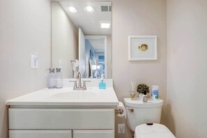 A bathroom with a white sink, mirror, and toilet. There are toiletries on the sink and toilet. - 2nd Floor Condo with Balcony, Shared Pool/HT/Tennis, AC (Bethany Beach)