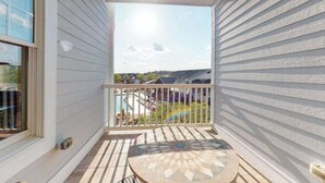 Een balkon met uitzicht op een zwembad en een heldere lucht.