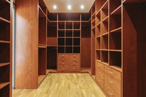 A walk-in closet with wooden shelving, drawers, and a herringbone-patterned floor. - Cascais Golden Horizon By Clama Retreats (Cascais)