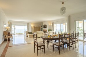 A spacious dining area with a large table, multiple chairs, and a chandelier. - Cascais Golden Horizon By Clama Retreats (Cascais)