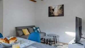 A modern living room with a grey sofa, blue chair, and a dining table with bread and juice.
