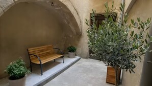 A stone archway, a wooden bench, potted plants, and a staircase.