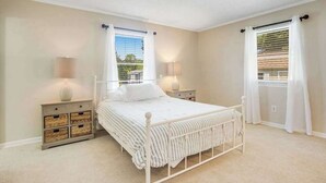 Una camera da letto con un letto, comodini, una finestra con tende e vista sull'esterno.