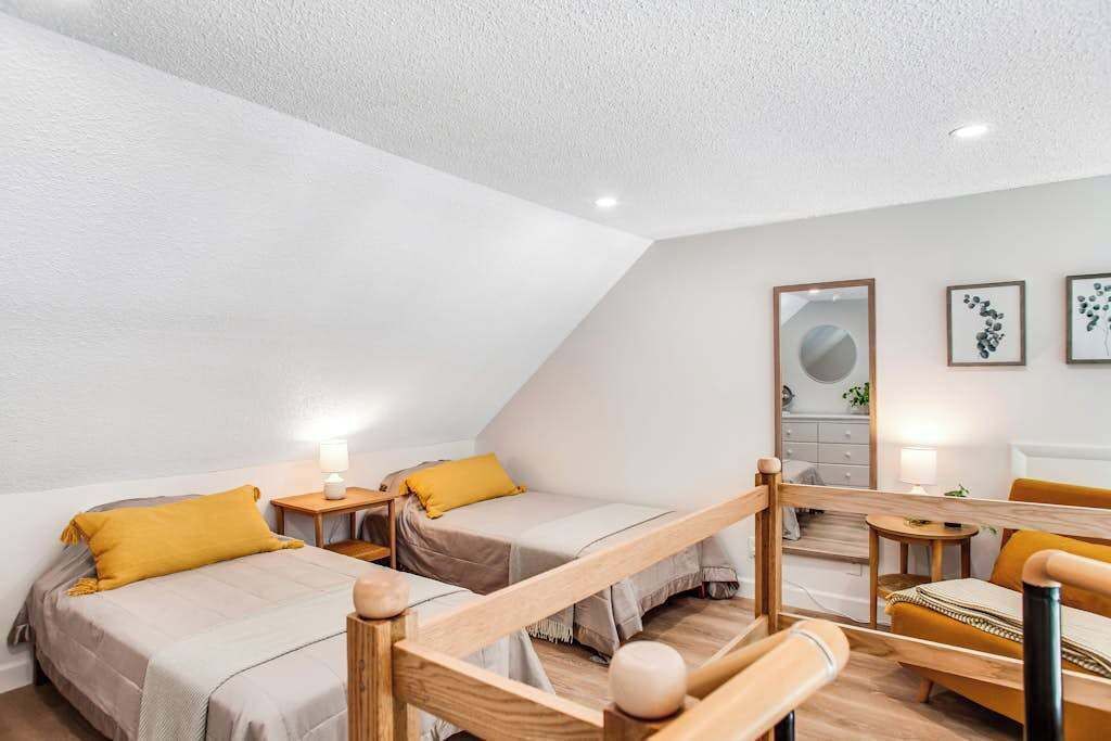 Une pièce moderne et bien éclairée, avec deux lits, un banc en bois et une petite table.