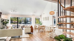 Un espace de vie moderne comprenant un coin repas, un escalier et de grandes fenêtres.