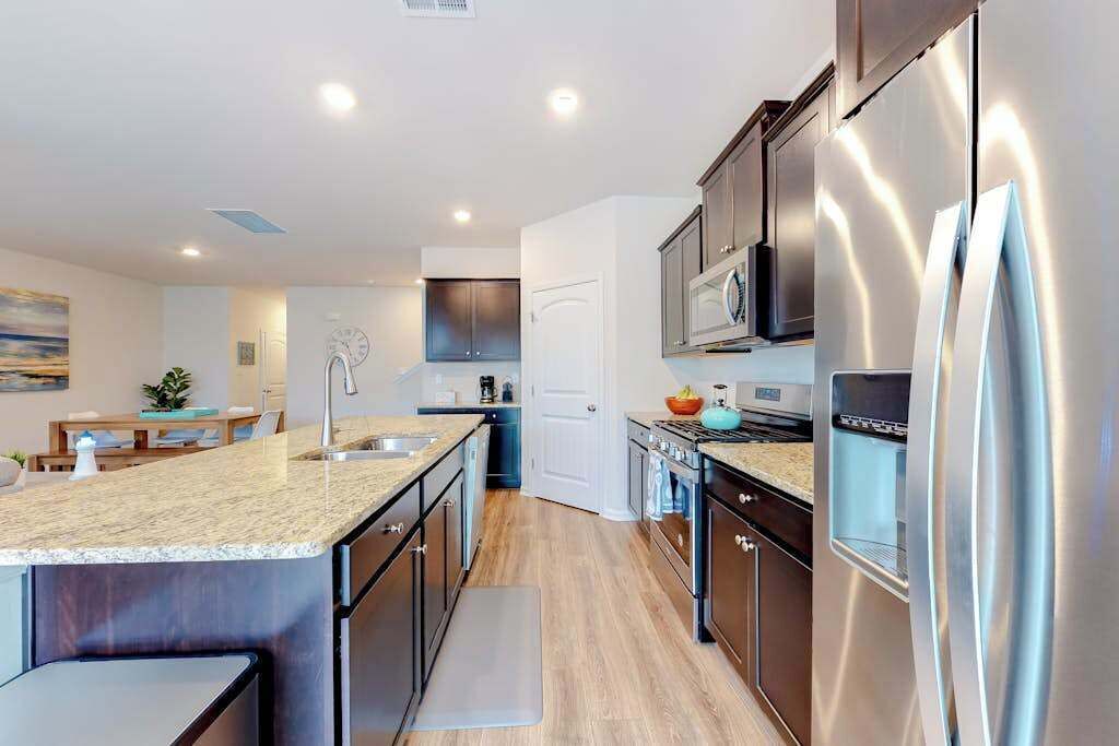 A modern kitchen with stainless steel appliances, a granite countertop, and a wooden floor.
