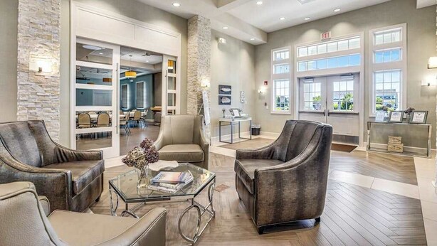 A spacious lobby with leather armchairs, a glass coffee table, and a reception desk. - Ocean View Beach Club home with fast WiFi, central A/C, & community amenities (Ocean View)