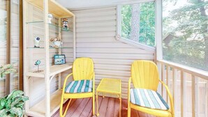 En balkong med två gula stolar, ett litet bord och en vit hylla med diverse föremål.