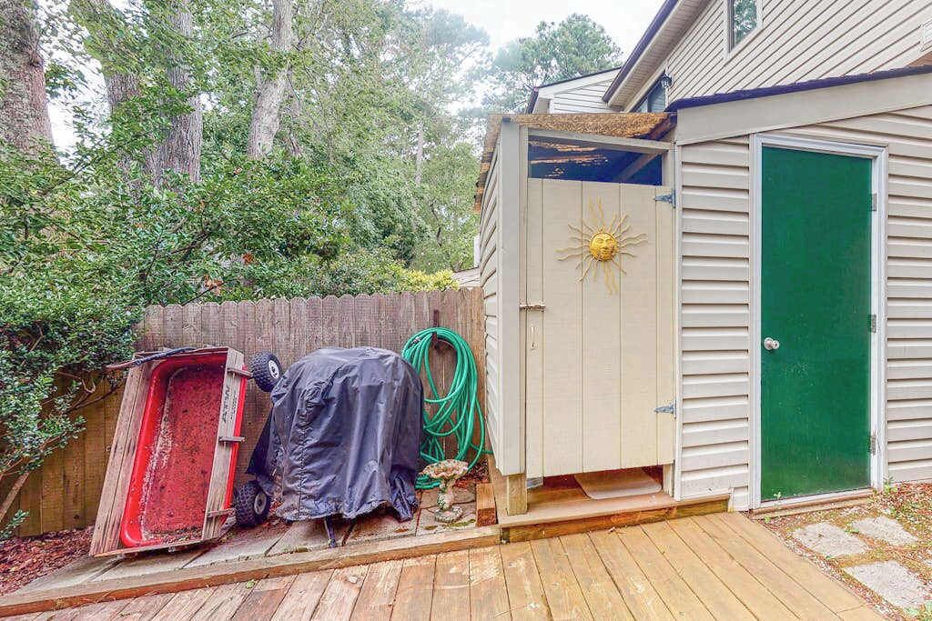 A wooden deck, a shed with a sun emblem, and a green door.