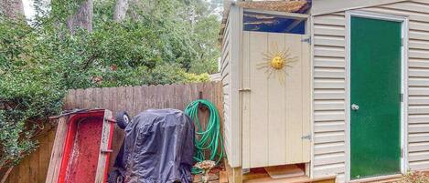 A wooden deck, a shed with a sun emblem, and a green door.