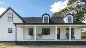 A white two-story house with a covered porch, numbered 30708, featuring a simple, symmetrical design. - Fully renovated ranch home with large patio and firepit (Dagsboro)