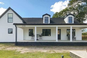A white two-story house with a covered porch, numbered 30708, featuring a simple, symmetrical design. - Fully renovated ranch home with large patio and firepit (Dagsboro)