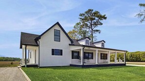A two-story house with a covered porch and a gravel driveway. - Fully renovated ranch home with large patio and firepit (Dagsboro)