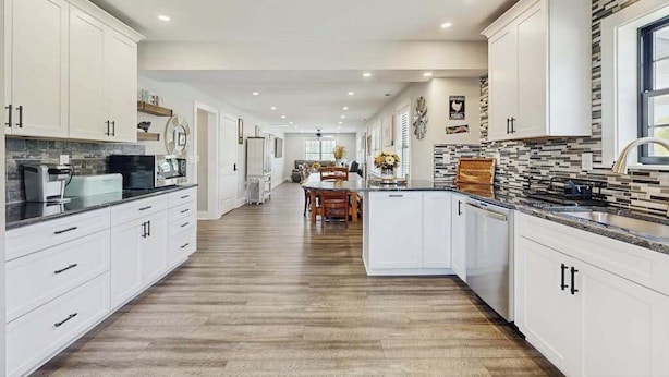 A spacious kitchen with white cabinetry, a central island, and a dining area with a table and chairs. - Fully renovated ranch home with large patio and firepit (Dagsboro)