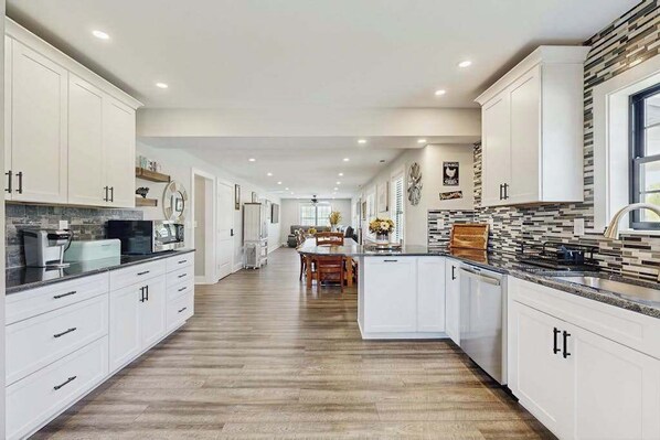 A spacious kitchen with white cabinetry, a central island, and a dining area with a table and chairs. - Fully renovated ranch home with large patio and firepit (Dagsboro)