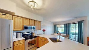 A modern kitchen with wooden cabinets, stainless steel appliances, and a large island with a sink.