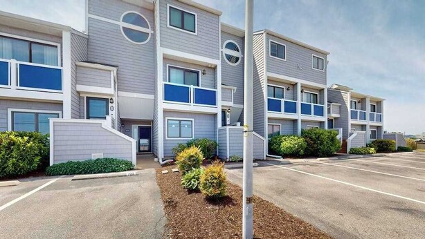 A multi-story residential building with a parking lot in front. - East of Sun condo with water-view patio, on-site pool & tennis - near beach (Fenwick Island)