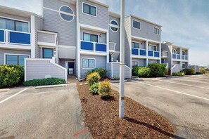 Un immeuble résidentiel à plusieurs étages avec un parking situé à l’avant.