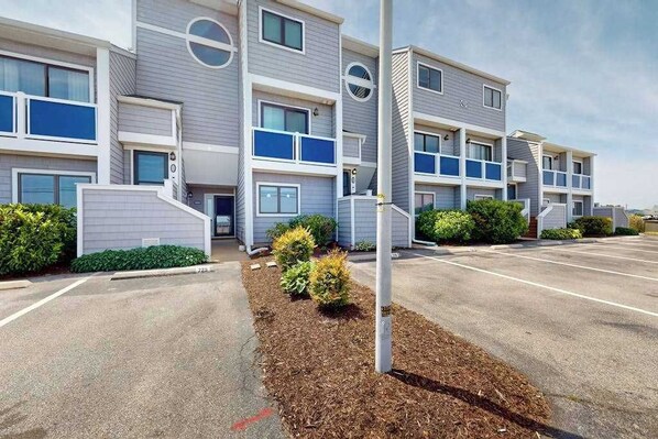 A multi-story residential building with a parking lot in front. - East of Sun condo with water-view patio, on-site pool & tennis - near beach (Fenwick Island)