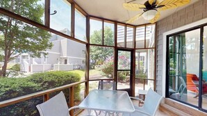 A sunroom with large windows, a glass table, and chairs.