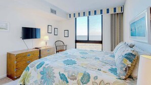 Quarto com cama, televisão, escrivaninha e janela.