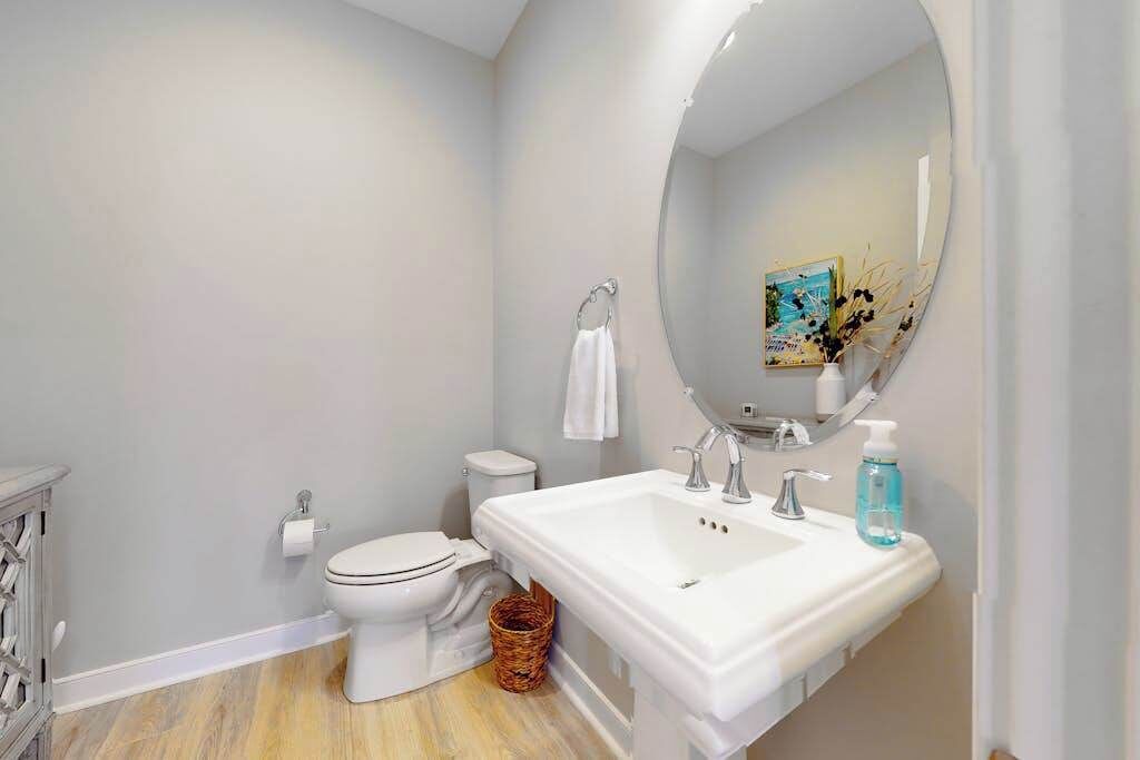 A bathroom with a toilet, sink, and mirror.