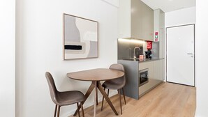 A modern kitchen with a dining area, including a table and chairs, a refrigerator, and a coffee machine. - GuestReady - Studio in Cedofeita (Porto)