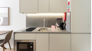 A modern kitchen with a built-in oven, a coffee maker, and a sink. - GuestReady - Studio in Cedofeita (Porto)