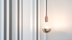 A light bulb hanging from a cord against a wall with vertical slats. - GuestReady - Studio in Cedofeita (Porto)