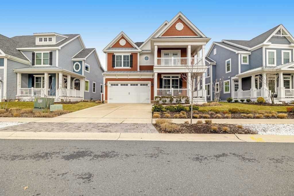 A row of two-story houses with front porches, a garage, and a well-maintained lawn.