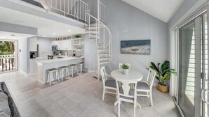 A modern interior with a kitchen, dining area, and a spiral staircase. - Sea Colony condo with pools, hot tub, tennis, gym, & private deck (Bethany Beach)