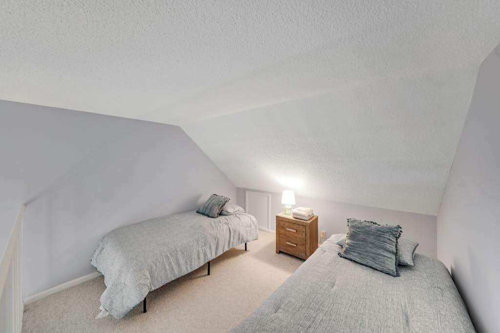 Un apartamento pequeño de una habitación con dos camas, una mesita de noche y una lámpara.