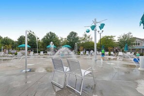 Ein Wasserspiel mit Fontänen, Sitzgelegenheiten und Sonnenschirmen im Freien.