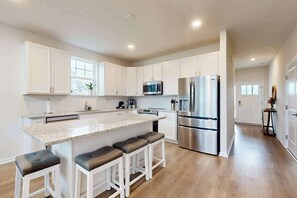 A modern kitchen with white cabinets, stainless steel appliances, and a granite countertop. - Friendship Creek dog-friendly townhome with pool, dog parks, bikes, & W/D (Frankford)