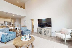 A spacious living room with a flat-screen TV, two sofas, a dining area, and a kitchen in the background. - Friendship Creek dog-friendly townhome with pool, dog parks, bikes, & W/D (Frankford)