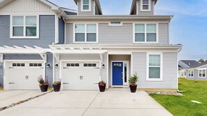 Een woonhuis met twee verdiepingen, een garage, een overdekte oprit en een blauwe voordeur.