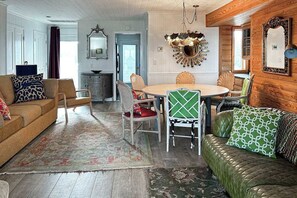 A living room with a sofa, chairs, a dining table, and a fireplace. - Dog-friendly oceanfront escape at Lewes with fast WiFi & AC - right on the beach (Lewes)