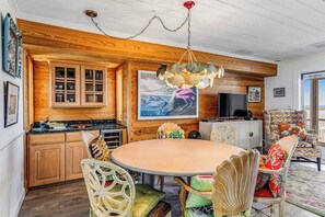 A wooden interior with a round table, chairs, a television, and a large painting. - Dog-friendly oceanfront escape at Lewes with fast WiFi & AC - right on the beach (Lewes)