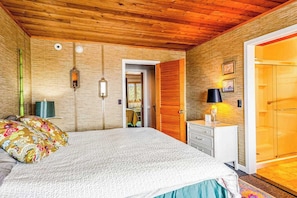 A bedroom with a wooden ceiling, a bed with patterned pillows, a bedside table with a lamp, and a wardrobe. - Dog-friendly oceanfront escape at Lewes with fast WiFi & AC - right on the beach (Lewes)
