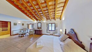 Un dormitorio con techo de madera, una cama, un aparador, una silla y una ventana.