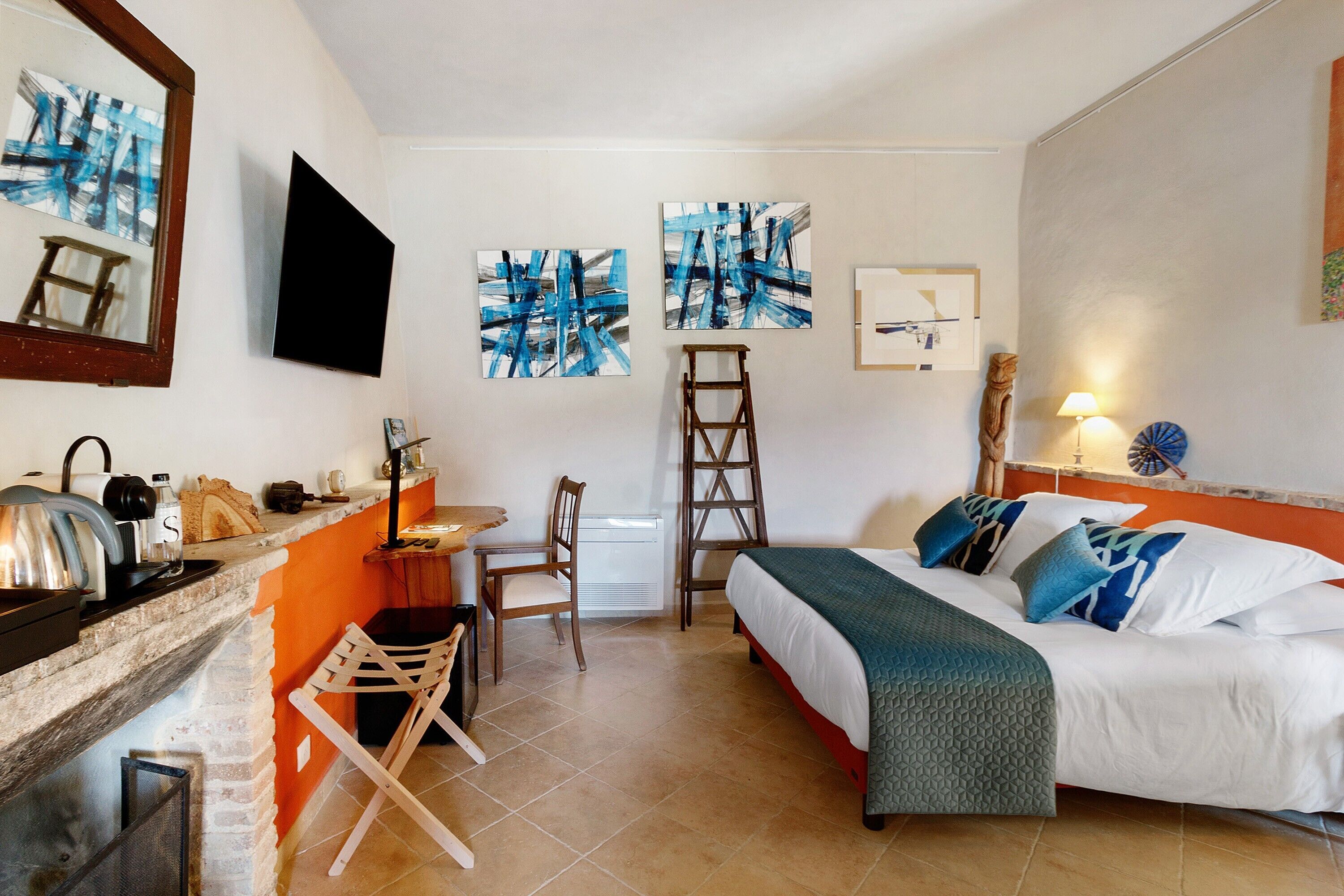 Une pièce comprenant un lit, un bureau, une chaise, une échelle et des œuvres d’art accrochées aux murs.