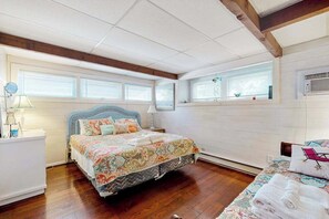 A bedroom with a bed, a bedside table, a lamp, and a window. - Town of Dewey Beach dog friendly condo with washer/dryer & free WIFI (Dewey Beach)