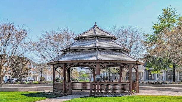 A gazebo with a hexagonal roof and open sides, surrounded by a paved area and trees. - Beautiful condo near ocean with pool, fast WiFi, central AC & washer/dryer (Lewes)