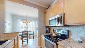 A kitchen with wooden cabinets, a stainless steel oven, a microwave, and a granite countertop. - Beautiful condo near ocean with pool, fast WiFi, central AC & washer/dryer (Lewes)
