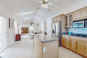 A spacious kitchen with wooden cabinets, a central island, and a ceiling fan. - Mill Pond Acres home w/pool table, Xbox X, free WIFI (Lewes)