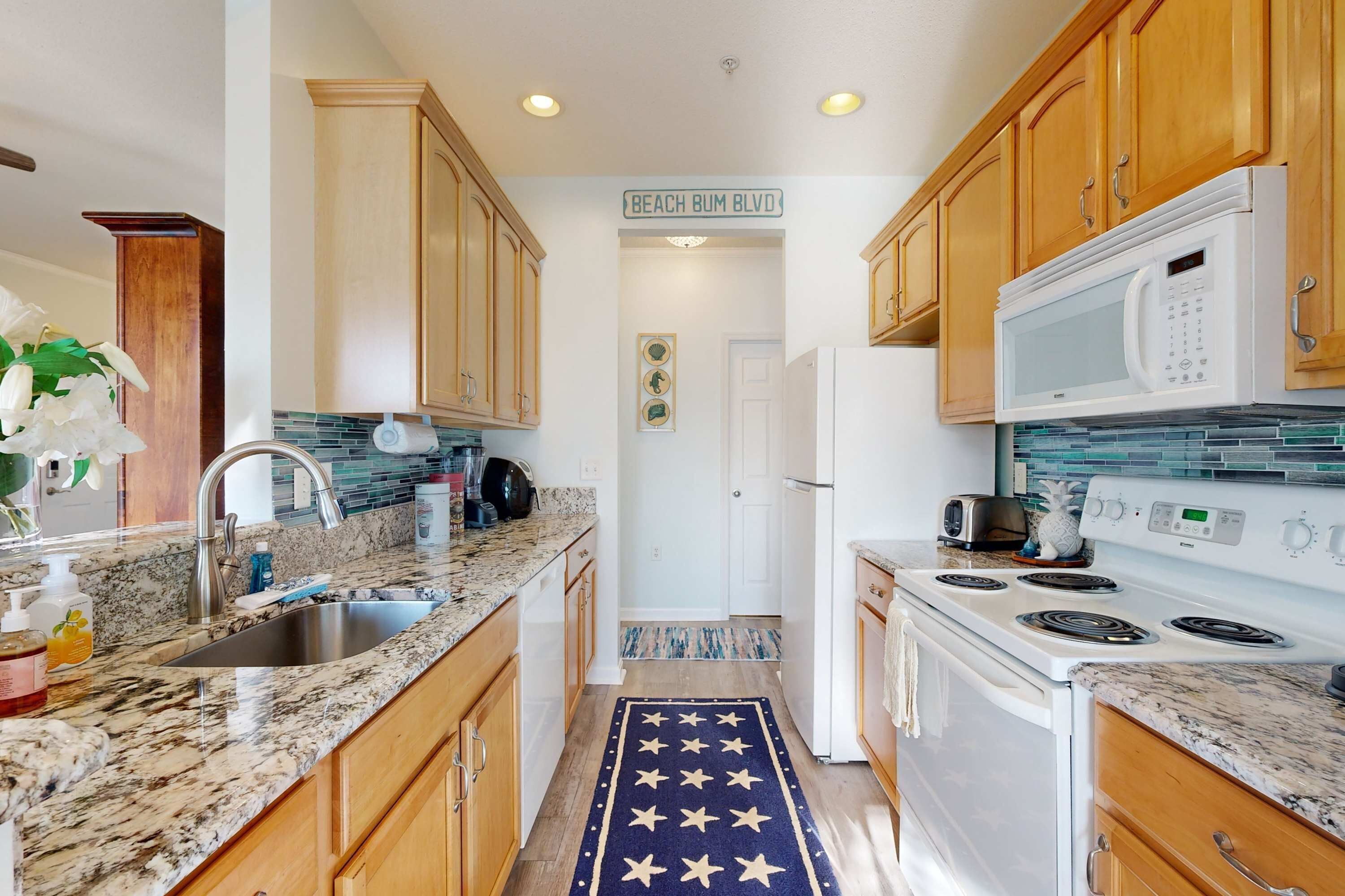 A kitchen with wooden cabinets, a granite countertop, a white stove, and a microwave.